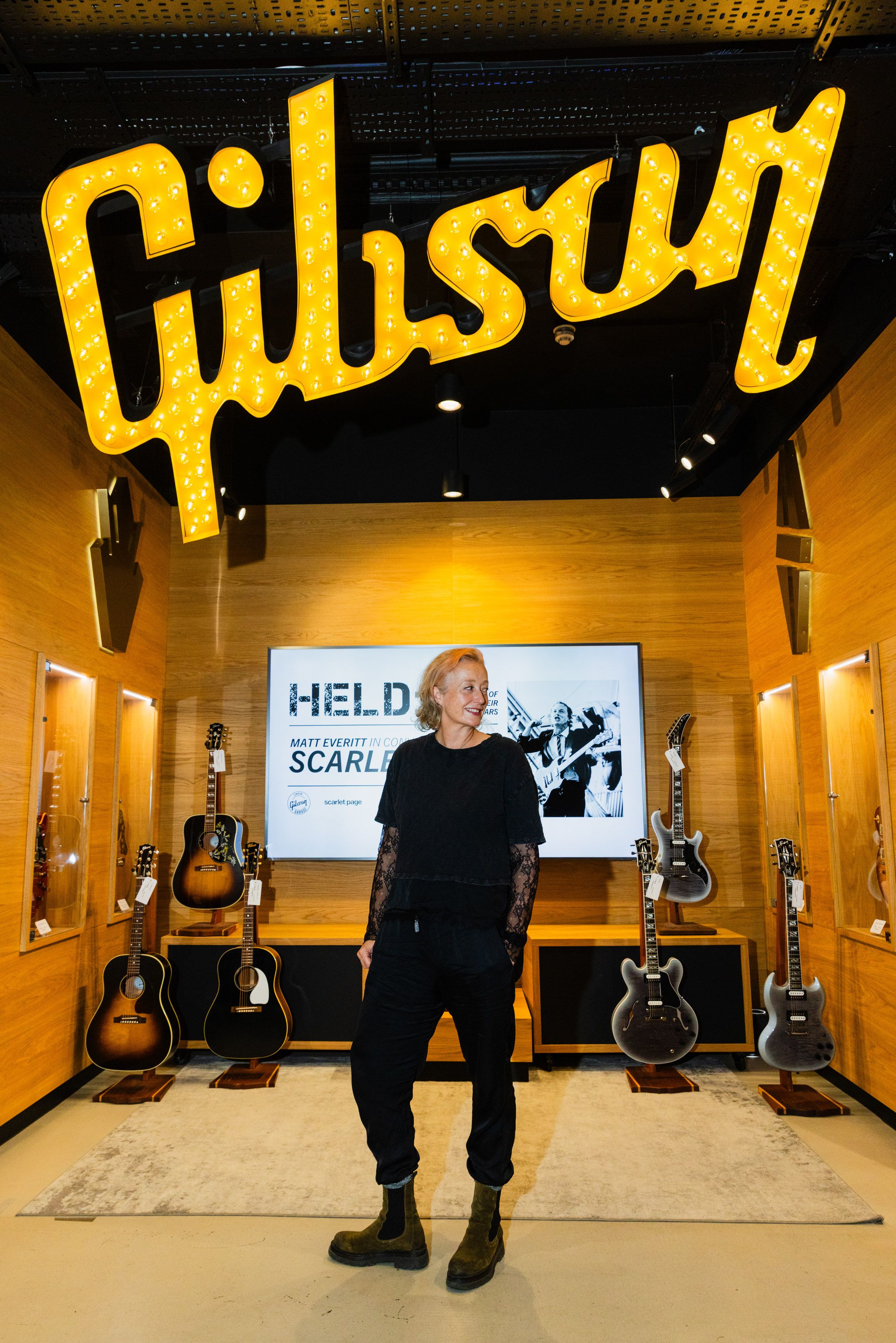 Scarlet Page standing beneath the Gibson sign at the entrance to the HELD exhibition